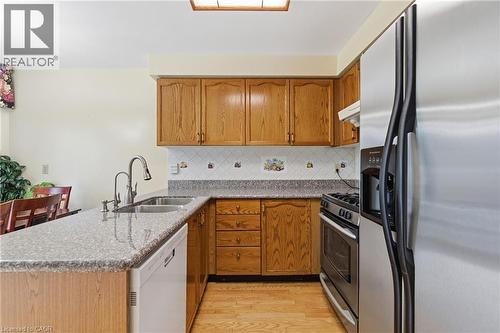 Kitchen with stainless steel appliances, a peninsula, light stone countertops, and decorative backsplash - 3372 Bobwhite Mews, Mississauga, ON 