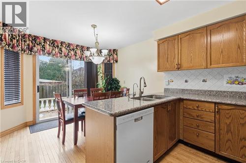 Kitchen with white dishwasher, tasteful backsplash, decorative light fixtures, a peninsula, and dark stone countertops - 3372 Bobwhite Mews, Mississauga, ON 