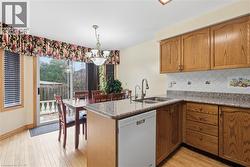 Kitchen with white dishwasher, tasteful backsplash, decorative light fixtures, a peninsula, and dark stone countertops - 