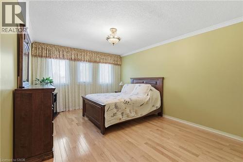 Bedroom featuring a textured ceiling, light wood-style flooring, and ornamental molding - 3372 Bobwhite Mews, Mississauga, ON 