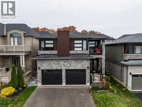 View of front of home featuring stone siding, asphalt driveway, a balcony, and a garage - 4040 Stadelbauer Drive, Beamsville, ON - Outdoor With Facade