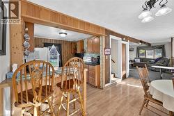 Dining space with wood walls, stairs, light wood finished floors, and a chandelier - 