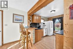Kitchen with brown cabinets, a breakfast bar, light wood-style flooring, dark countertops, and white microwave - 