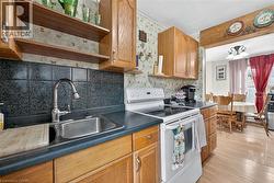 Kitchen featuring white range with electric cooktop, tasteful backsplash, dark countertops, open shelves, and light wood-style floors - 