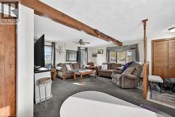 Carpeted living area featuring beamed ceiling, healthy amount of natural light, and ceiling fan - 