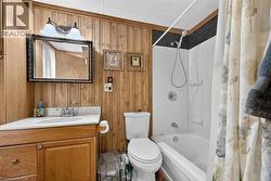 Bathroom featuring wood walls, shower / tub combo, and vanity - 