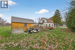Back of house featuring a gambrel roof, a yard, a wooden deck, and a shed - 