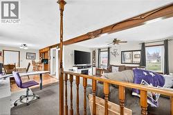 Living area with beam ceiling, carpet floors, a ceiling fan, and a fireplace - 