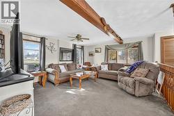 Living room with beamed ceiling, light colored carpet, and a ceiling fan - 
