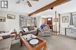 Carpeted living area with beamed ceiling and ceiling fan - 