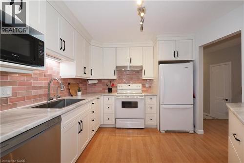 Kitchen featuring white & SS appliances, light wood flooring, brick style backsplash, and white cabinetry - 511 Oakvale Drive Unit# 1, Waterloo, ON - Indoor Photo Showing Kitchen