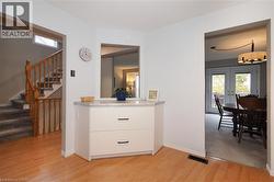Kitchen view of island style white cabinet, stairway to second floor, light wood finished floors, and dining room - 
