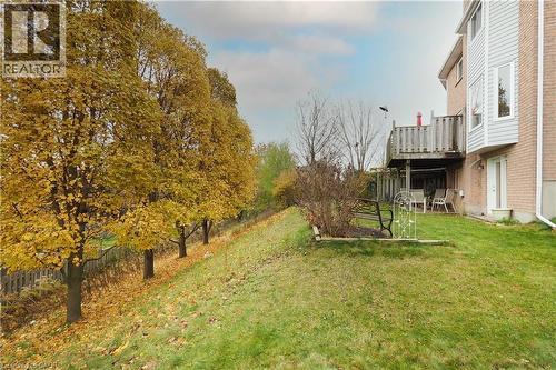 View of spacious lawn bordered by mature trees and featuring a lower level patio area and main floor wooden deck - 511 Oakvale Drive Unit# 1, Waterloo, ON - Outdoor
