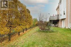 View of spacious lawn bordered by mature trees and featuring a lower level patio area and main floor wooden deck - 