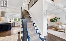 Stairway featuring beam ceiling, coffered ceiling, wood finished floors, and ornamental molding - 