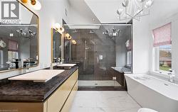 Full bathroom featuring a chandelier, plenty of natural light, a freestanding tub, and a stall shower - 