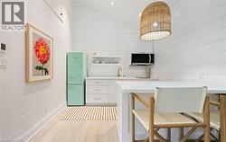 Kitchen featuring white cabinetry, light wood-style flooring, open shelves, a kitchen bar, and wooden walls - 