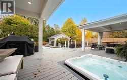 Deck with area for grilling, an outdoor structure, an outdoor hangout area, and view of wooded area - 