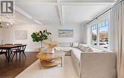 Living room with dark wood-style flooring, beamed ceiling, coffered ceiling, a chandelier, and wood walls - 