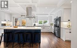 Kitchen featuring white cabinetry, beamed ceiling, a breakfast bar, stainless steel fridge with ice dispenser, and backsplash - 
