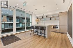 Kitchen with open shelves, a breakfast bar area, decorative light fixtures, light wood-style floors, and light brown cabinetry - 