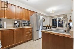 Kitchen with brown cabinetry, appliances with stainless steel finishes, light countertops, and light tile patterned floors - 