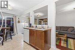 Kitchen featuring light countertops, brown cabinets, dishwasher, light tile patterned floors, and open floor plan - 