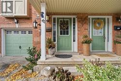 Property entrance featuring a porch, brick siding, and a garage - 