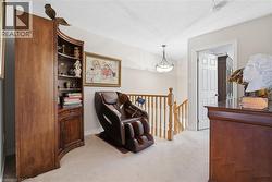 Living area featuring a textured ceiling, light carpet, and an upstairs landing - 