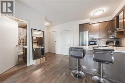 Kitchen featuring dark wood finished floors, stainless steel fridge, a peninsula, black microwave, and light countertops - 