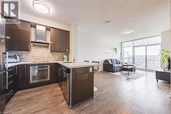 Kitchen with a peninsula, a sink, appliances with stainless steel finishes, expansive windows, and wall chimney range hood - 