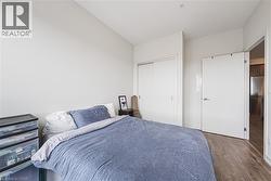 Bedroom featuring stainless steel built in fridge, a closet, and dark wood finished floors - 