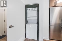 Laundry room with stacked washer / dryer, laundry area, and wood finished floors - 