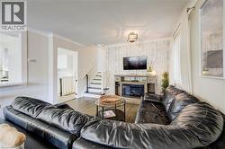 Living room with a glass covered fireplace, wood finished floors, and stairway - 