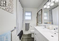 Full bath featuring natural light, vanity, wainscoting, and tile walls - 