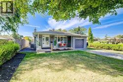 View of front of home with covered porch, brick siding, driveway, a chimney, and a garage - 