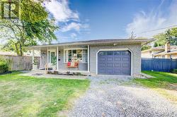 View of front of home with a porch, brick siding, driveway, and a garage - 