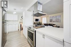 Kitchen featuring island range hood, stainless steel appliances, white cabinets, and open floor plan - 