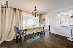 Dining space with a chandelier and dark wood-type flooring - 