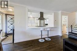 Kitchen featuring dark wood finished floors, a breakfast bar, island exhaust hood, white cabinets, and stainless steel appliances - 