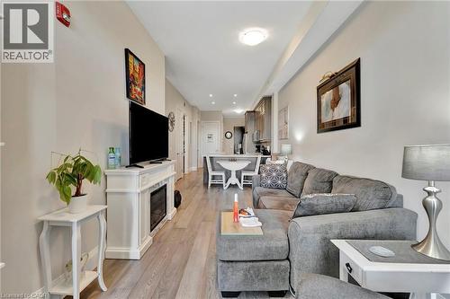 Living area featuring light wood finished floors and a glass covered fireplace - 85B Morrell Street Unit# 117, Brantford, ON - Indoor Photo Showing Living Room