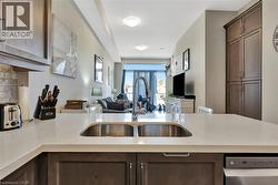 Kitchen featuring open floor plan, dishwasher, light stone counters, dark brown cabinetry, and a peninsula - 