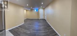 Below grade area with recessed lighting, freestanding refrigerator, and wood finished floors - 