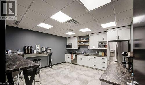 Kitchen with open shelves, dark countertops, appliances with stainless steel finishes, a paneled ceiling, and white cabinetry - 55 Progress Drive E, Aylmer, ON 
