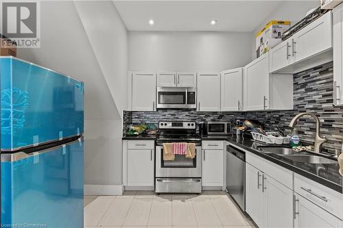 Kitchen featuring dark countertops, backsplash, a sink, and stainless steel appliances - 181 West Avenue N, Hamilton, ON - Indoor Photo Showing Kitchen With Double Sink