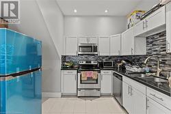 Kitchen featuring dark countertops, backsplash, a sink, and stainless steel appliances - 