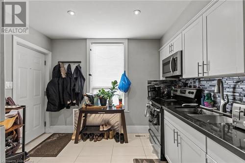 Kitchen with white cabinets, baseboards, tasteful backsplash, appliances with stainless steel finishes, and a sink - 181 West Avenue N, Hamilton, ON - Indoor Photo Showing Kitchen