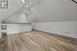Bonus room featuring wood finished floors, baseboards, vaulted ceiling, and visible vents - 