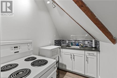 Kitchen with light wood-style flooring, white appliances, tasteful backsplash, white cabinetry, and a sink - 181 West Avenue N, Hamilton, ON - Indoor Photo Showing Kitchen