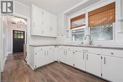 Kitchen featuring open shelves, white cabinetry, tasteful backsplash, dark wood-type flooring, and a textured ceiling - 
